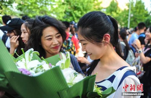 資料圖：山東濟(jì)南眾多考生手捧鮮花在家長(zhǎng)的簇?fù)硐職g快告別高考。中新社記者 張勇 攝
