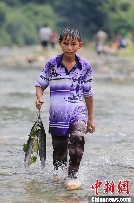 圖為7月9日，一名男孩在鬧魚節(jié)活動中抓到了兩條魚。譚凱興 攝