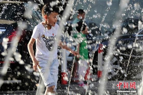 山西太原最高溫36℃,兒童在噴泉周圍戲水消暑。