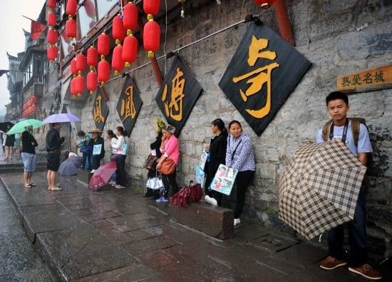 　4月29日上午11時20分，一些游客和古城當?shù)氐木用穸阍谝粋€酒吧的屋檐下避雨。這些當?shù)鼐用褚詾橛慰团恼罩\生，一場降雨讓他們的生意更加清淡。