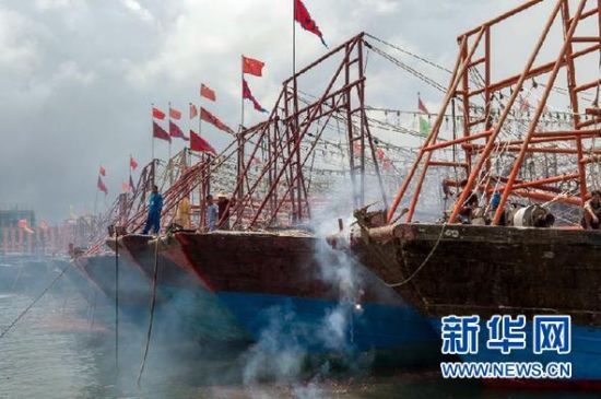 2013年8月1日 南海開漁日 臨高迎新港 8月1日，海南省臨高縣漁民在船上鳴放鞭炮慶祝武蓮港開港。