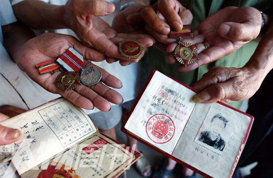 幾位志愿軍老兵展示自己的立功證、傷殘軍人證與勛章