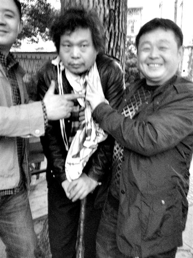 兩名接訪人員與患有癌癥的訪民段新德合影時(shí)，面帶笑容擺出勝利的手勢。