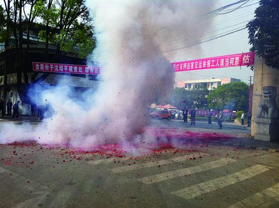 市民在普洱市主干道振興大道的金孔雀交通運(yùn)輸集團(tuán)有限公司門(mén)前燃放鞭炮，公司門(mén)前掛著“貪腐份子沈培平被查處，罪有應(yīng)得，大快人心?！钡臈l幅