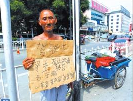老人舉著牌子在路邊等候失主。京華時報記者譚青攝