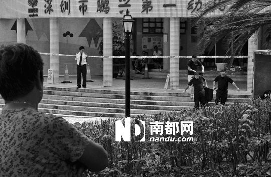 →7月19日，鵬興花園第一幼兒園門前，民警在現(xiàn)場進行完勘查取證后，園長和保安的尸體被運走。南都記者 徐文閣 攝