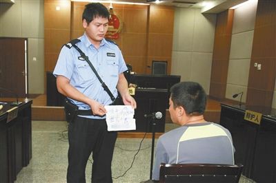昨日庭審中，法警向趙某出示其扎完車胎后所留辱罵公司的紙條。通訊員 李秀文 攝