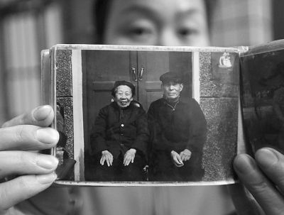 圖為孫女拿出兩位老人上世紀(jì)80年代在家門口的合影給記者看。記者楊濤 攝