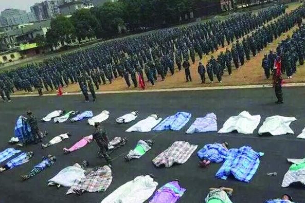 20多名女生躺在瀝青跑道上，身上嚴(yán)嚴(yán)實實地裹著棉被，接受太陽的照曬。