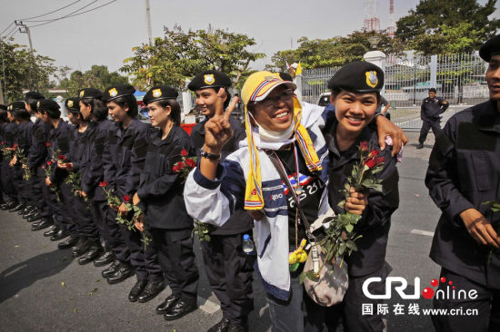 2013年12月03日,曼谷總理府與曼谷警署允許反政府示威民眾進入,雙方進入暫時“停戰(zhàn)”狀態(tài)迎接泰王生日。曼谷警察總署,女警們手持鮮花送給反政府示威民眾。圖片來源:Manish Swarup/東方IC