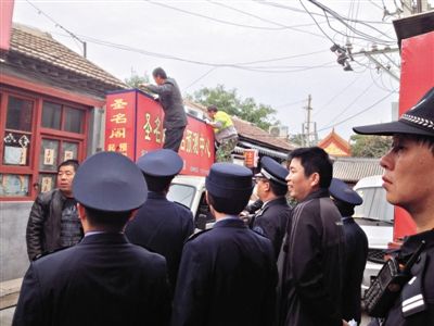 昨日下午,東城區(qū)工商、城管、公安等部門,對雍和宮附近的預(yù)測中心進行清理整頓,站在車頂?shù)膬擅と苏鸪患摇邦A(yù)測中心”的招牌。因雍和宮、白云觀等文化景點外聚集大量算命先生,被媒體稱為“算命一條街”。本版攝影/新京報記者 李寧 攝