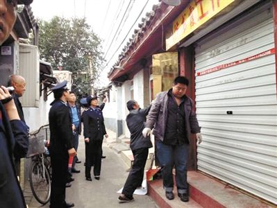 執(zhí)法人員拆除胡同里一家店面未經(jīng)審批的招牌。