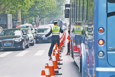 省人民醫(yī)院南門的路中間擺放反光錐，交警示意由西向東車輛從前方繞行。