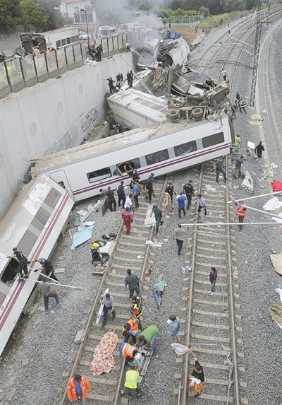 24日，救援人員在西班牙列車脫軌現(xiàn)場(chǎng)。一節(jié)車廂被強(qiáng)大的慣性拋上鐵道邊的高臺(tái)。