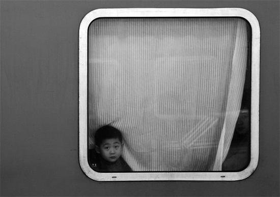 一個(gè)孩子把頭伸向窗外，他想再看送別的親人一眼