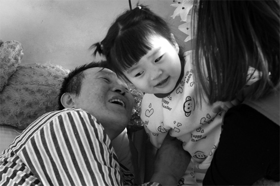 病床前李剛父女倆說著“悄悄話”，幸福的氣氛洋溢在病房中