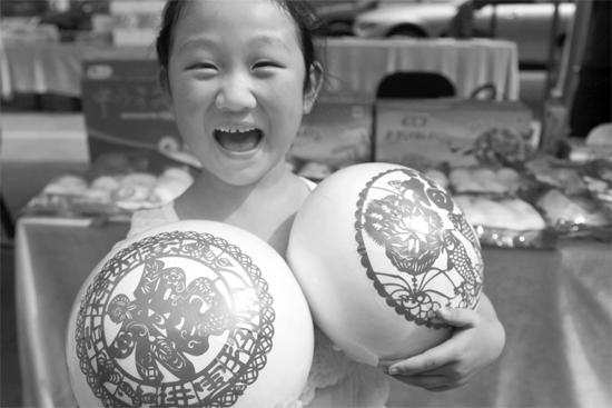 在2013河南食品安全宣傳周活動現(xiàn)場，一個小女孩抱著參展的特色大饅頭樂開了花