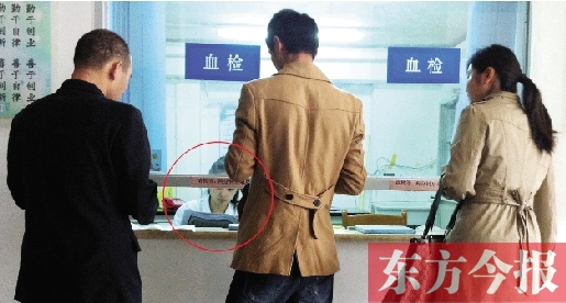 昨日，鄭州市二七區(qū)疾控中心辦證大廳，血檢窗口內(nèi)一名女工作人員，邊接受辦證者咨詢邊看報紙