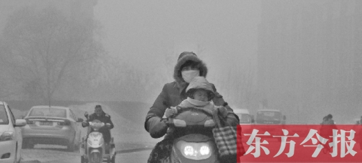 12月8日，鄭州市未來(lái)路上，一位市民帶著孩子在霧中騎行