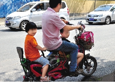 周先生騎著一輛低矮的電動(dòng)車帶著一對(duì)兒女，很不安全。