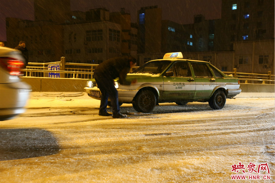 一位出租車司機(jī)在車輪前灑上雪，希望能增加輪胎的摩擦力。