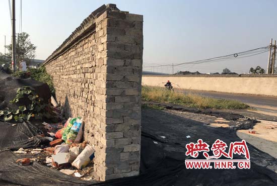 一墻之隔，一邊是道路，一邊是垃圾和荒草，市民質疑其為遮羞墻。