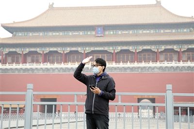 11月1日，北京大部分地區(qū)重度污染，一名游客戴著口罩在午門前揮手跟朋友打招呼。 實(shí)習(xí)生 王飛 攝