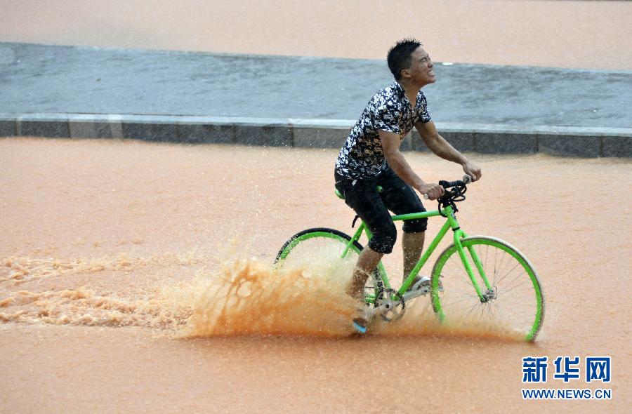 5月11日，一名行人在深圳街頭冒雨騎行。
