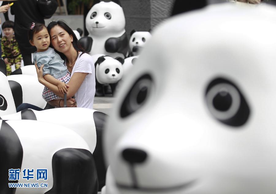 6月2日，一位家長(zhǎng)帶著孩子在上海街頭和大熊貓模型合影。