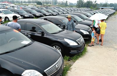 昨日，市民在山東棗莊一家拍賣公司場(chǎng)地上查看待拍賣公車。當(dāng)日，棗莊市103輛公車公開拍賣。新華社記者