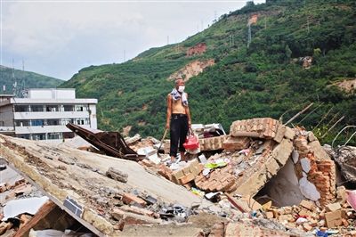 8月9日,龍頭山鎮(zhèn),一位老者在自家房屋廢墟上尋找家當(dāng)。