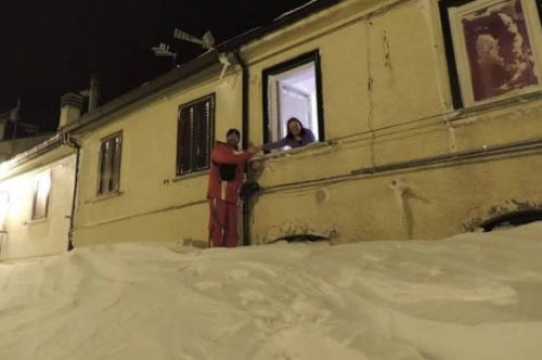 一個居民站在積雪上，可以與一名二樓鄰居在窗口握手。（來源：意大利氣象局）