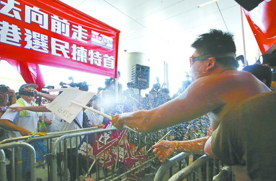17日，在香港立法會(huì)外，一名反對(duì)政改的男子向支持派人群投擲標(biāo)牌。