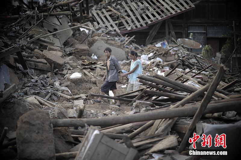 2014年8月5日，云南昭通龍頭山鎮(zhèn)老街，一對(duì)夫妻從居住房屋的廢墟中走過。