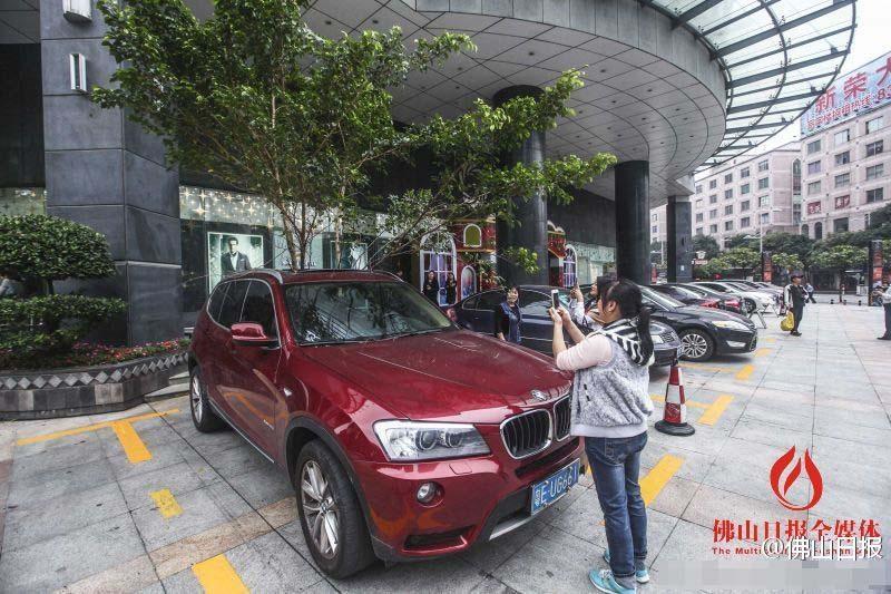 一輛停在停車位上的寶馬轎車，被墜落的樹枝砸中，樹枝徑直插入車內(nèi)，現(xiàn)場(chǎng)引發(fā)不少市民圍觀拍照。