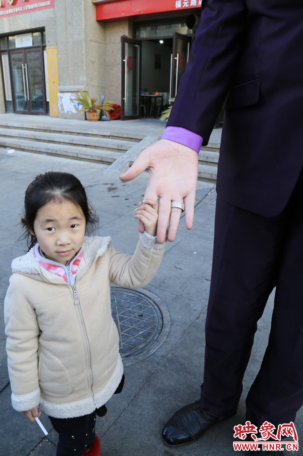 巨人“張歡”牽著一名漂亮的小女孩，兩人的手大小對比非常明顯。
