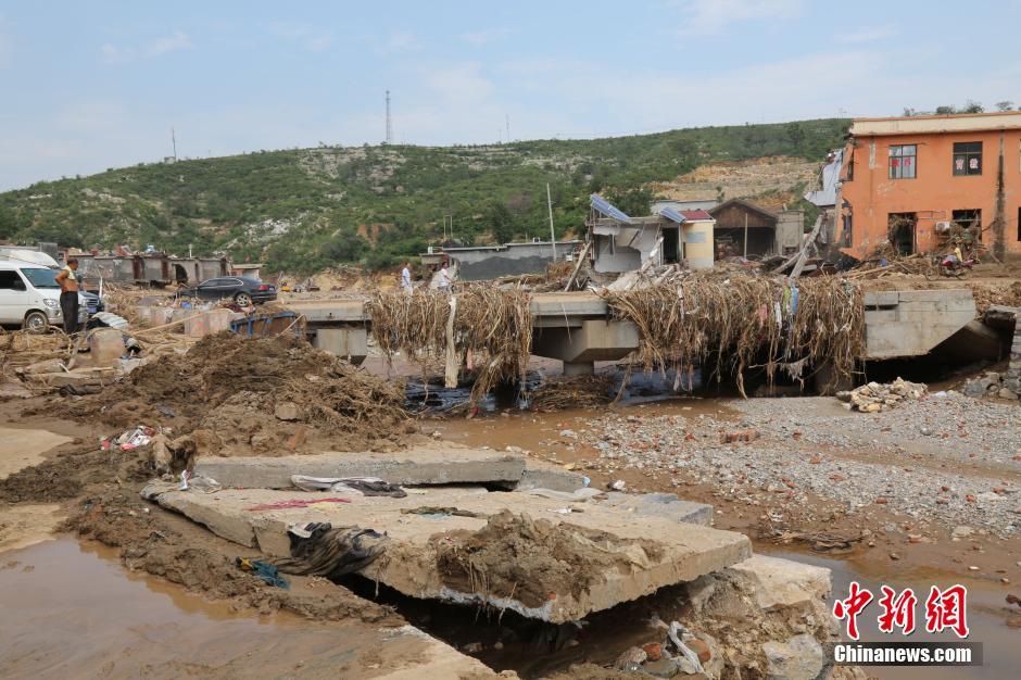 圖為洪水過(guò)后，坍塌的橋梁上遺落大量雜草。