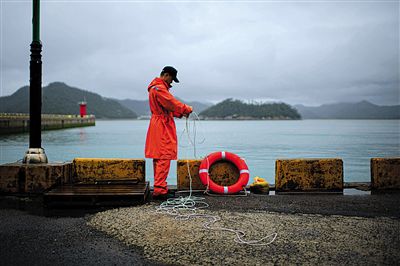 7月6日，韓國珍島，一名海岸警察在港口系救生圈。4月，客輪在珍島近海發(fā)生沉船事故后，仍有11人下落不明。