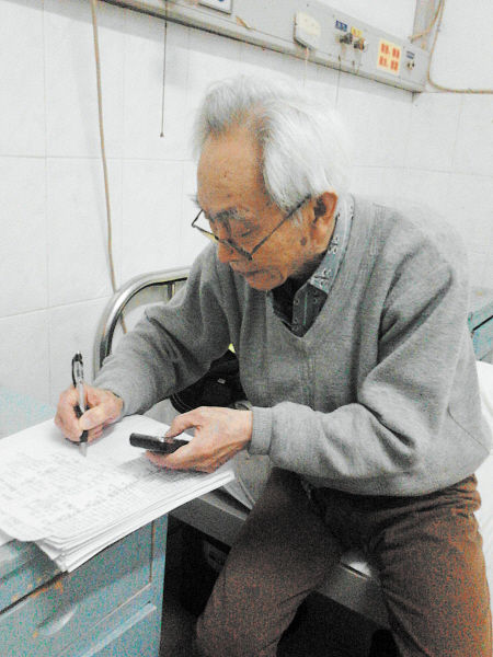 杜修源老人埋頭寫著特殊的“日記”。 李卓 攝