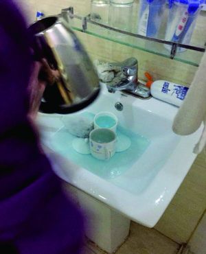 酒店服務(wù)員用潔廁液刷燒水壺和茶杯。