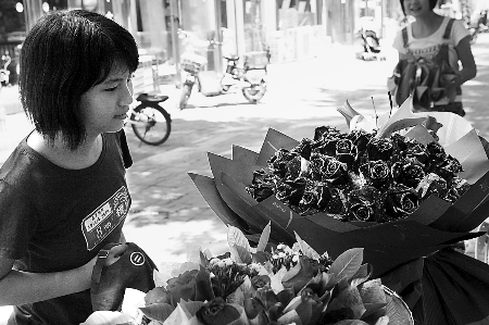 鄭州市農(nóng)業(yè)路一家花店擺放的玫瑰花吸引著一位過往女孩。