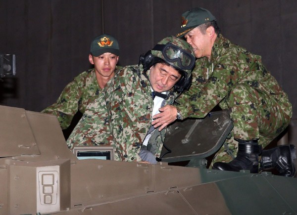 當地時間4月27日，日本千葉市，日本首相安倍晉三他身穿迷彩服頭戴鋼盔的登上展出中的日本陸上自衛(wèi)隊最新