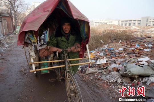 圖為老人走出窩棚，推著三輪車準備出去撿拾廢品。周小云 攝